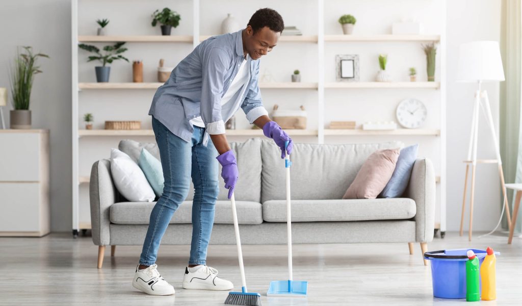 cheerful-black-guy-cleaning-living-room-holding-b-2021-09-04-02-50-46-utc.jpg